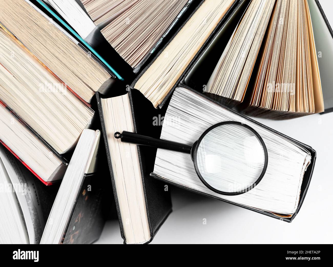 Lente di ingrandimento sopra il libro di carta aperto. Concetto di conoscenza, ricerca e studio. Foto Stock