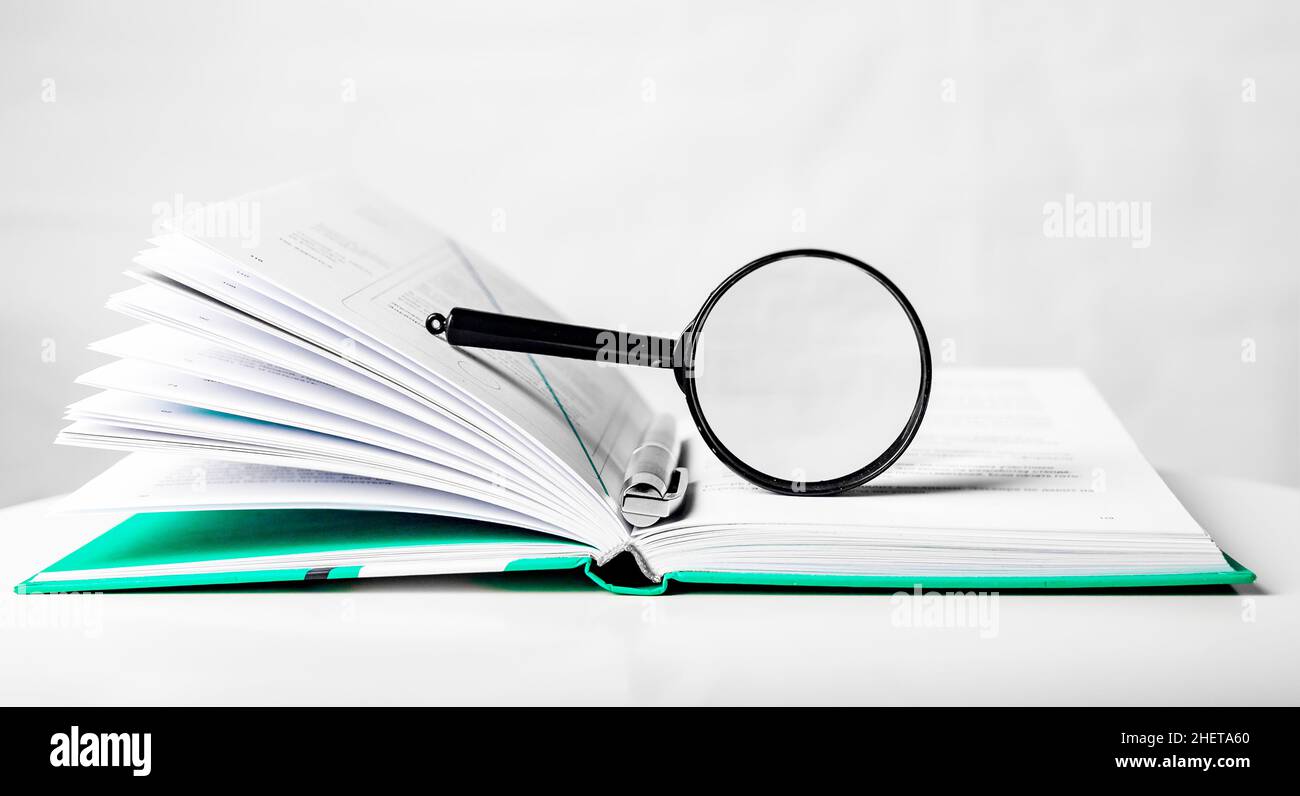Lente di ingrandimento su libro di carta di affari aperto. Concetto di conoscenza e studio. Foto Stock