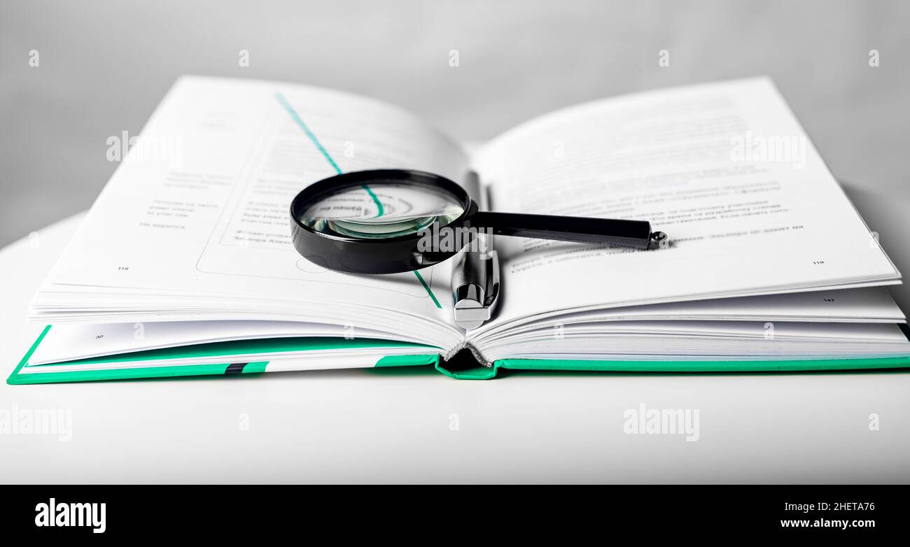 Lente di ingrandimento su libro di carta di affari aperto. Concetto di conoscenza e studio. Foto Stock