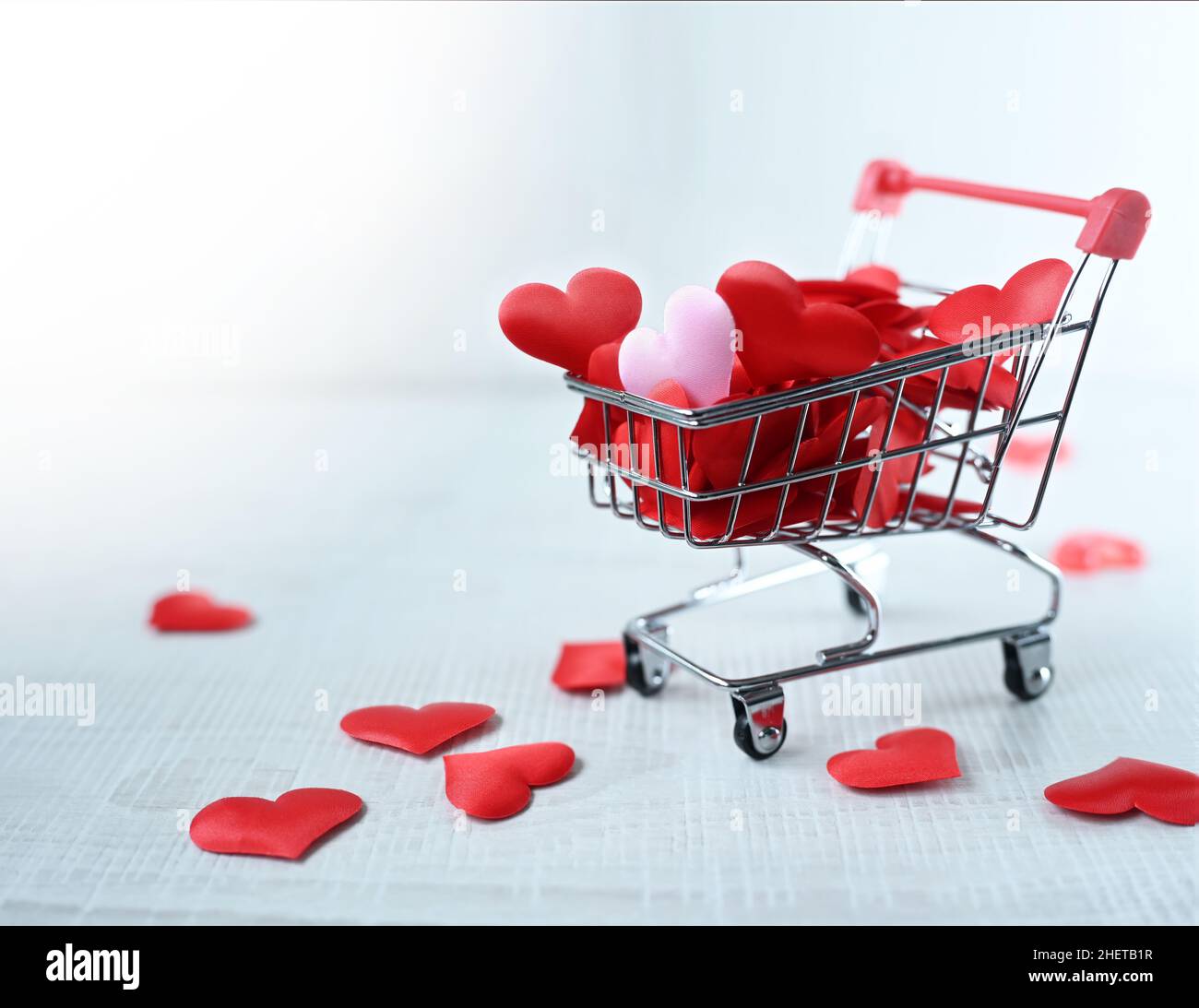 Carrello per lo shopping con cuori rosa isolato su sfondo grigio. Concetto di shopping. Foto Stock