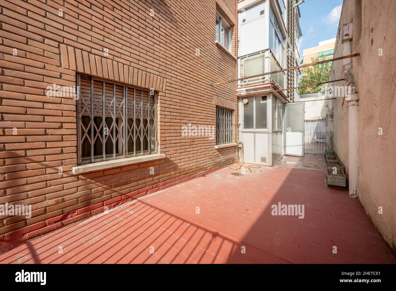 Patio al piano terra di un edificio con una facciata in mattoni di argilla e balconi in alluminio Foto Stock
