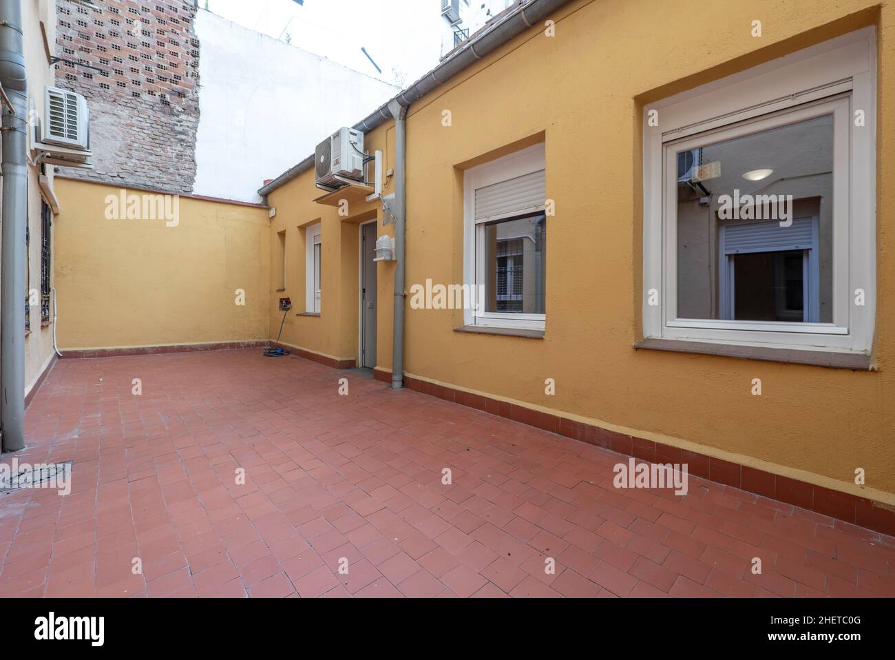 Casa al piano terra con diverse finestre e patio con pavimenti in argilla Foto Stock