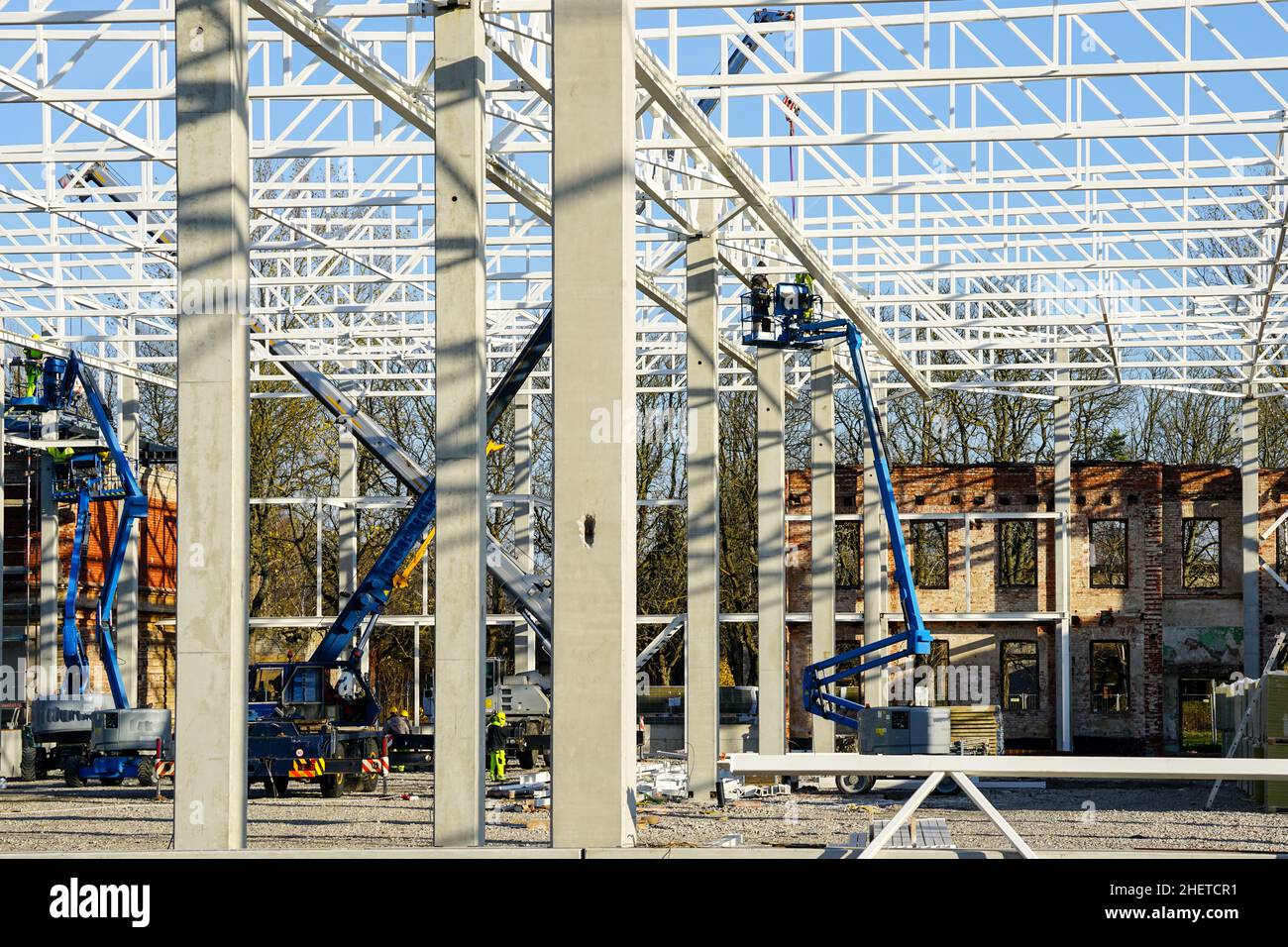 sollevatori a forbice semoventi e gru telescopica per l'installazione e l'assemblaggio di telai strutturali metallici in un nuovo edificio Foto Stock