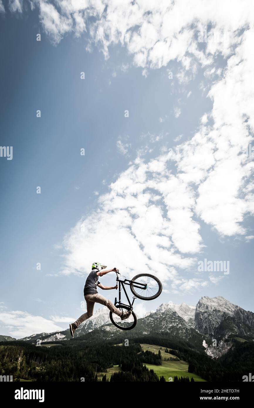 il giovane trick stunt biker salta in alto sulle montagne alp Foto Stock