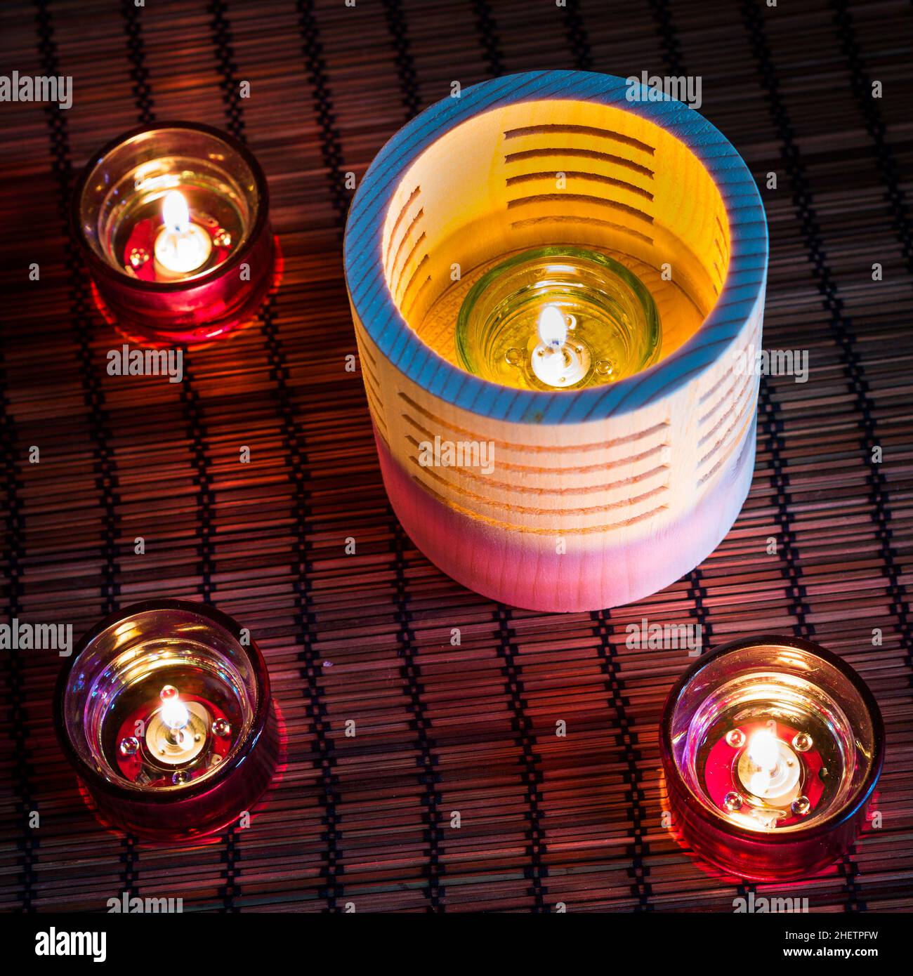 candele da tè in legno e vetro in piedi su un tappeto di canna Foto Stock