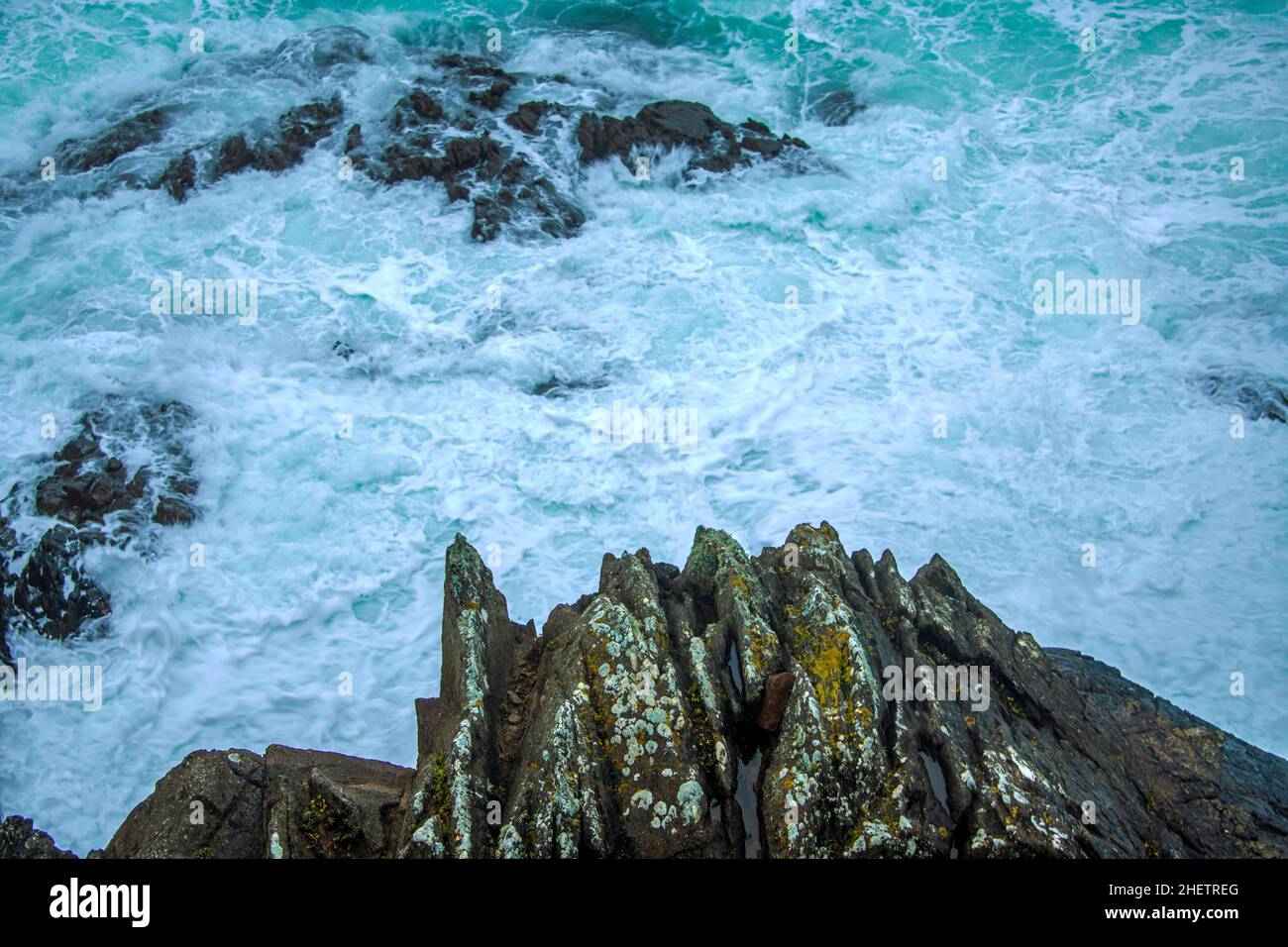 Onde selvatiche che colpiscono sulle grandi rocce della costa Foto Stock