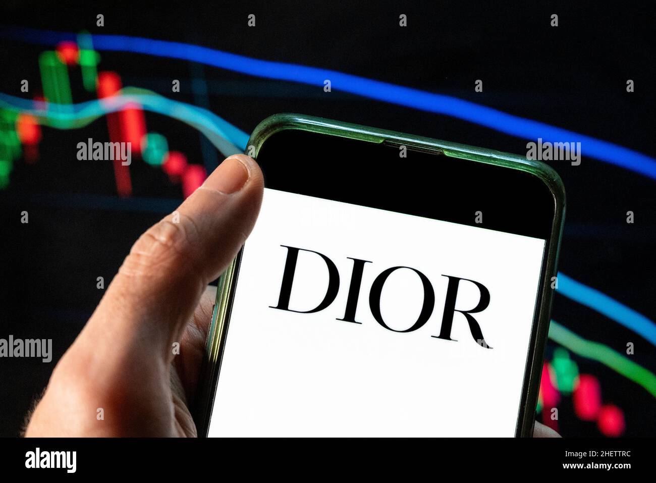 Cina. 4th Dic 2021. In questa illustrazione della foto il logo dei prodotti di lusso francesi, di abbigliamento e di bellezza Christian Dior, visto su uno smartphone con un grafico di indice di borsa economica sullo sfondo. (Credit Image: © Budrul Chukrut/SOPA Images via ZUMA Press Wire) Foto Stock