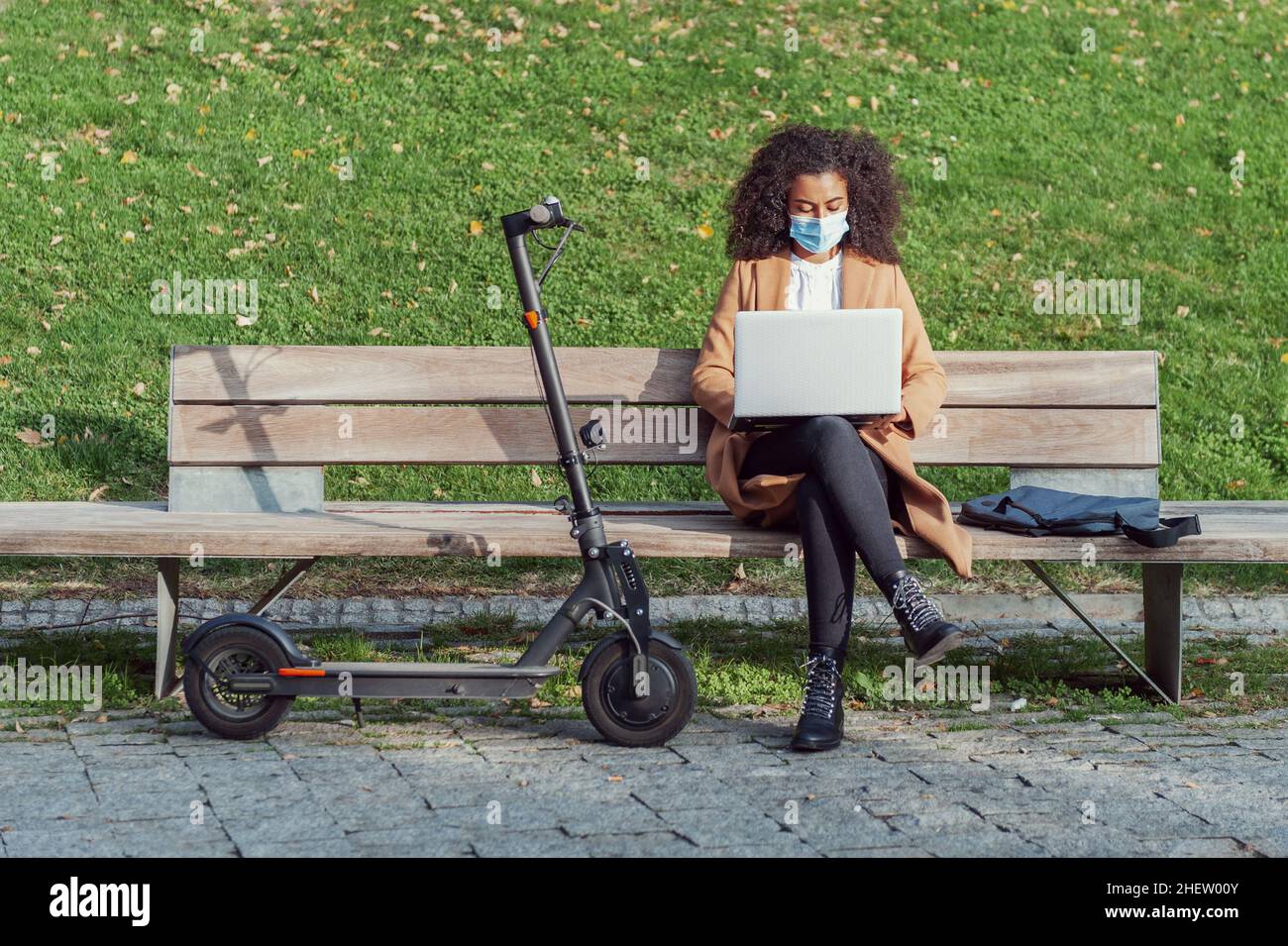 Donna seduta che lavora con il laptop e lo scooter elettrico Life Style indipendenza stile di vita sano Foto Stock