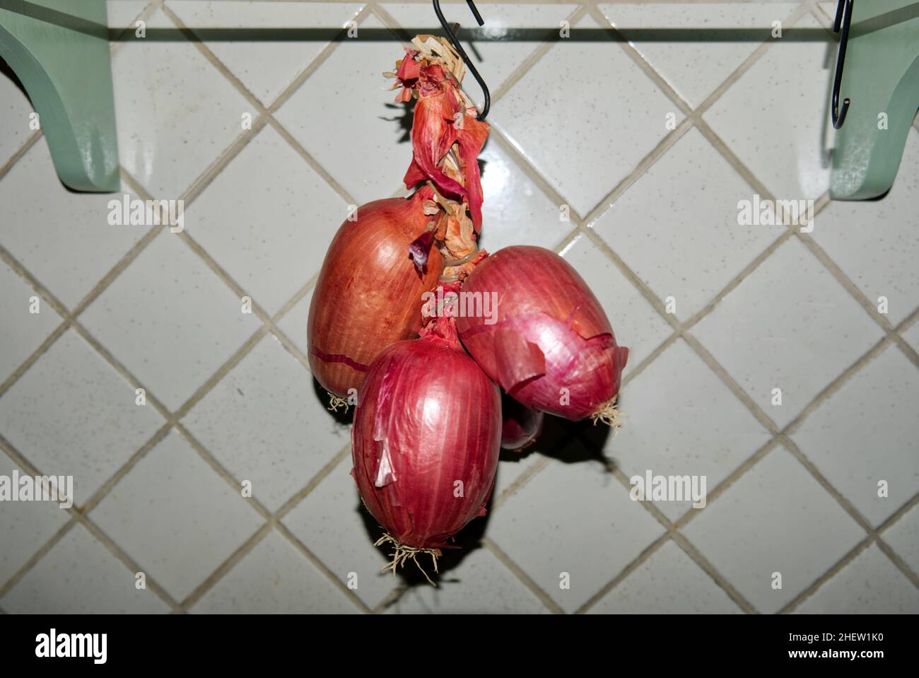 Cucina italiana: Una treccia di cipolline rosse dolci tropea appese in cucina Foto Stock