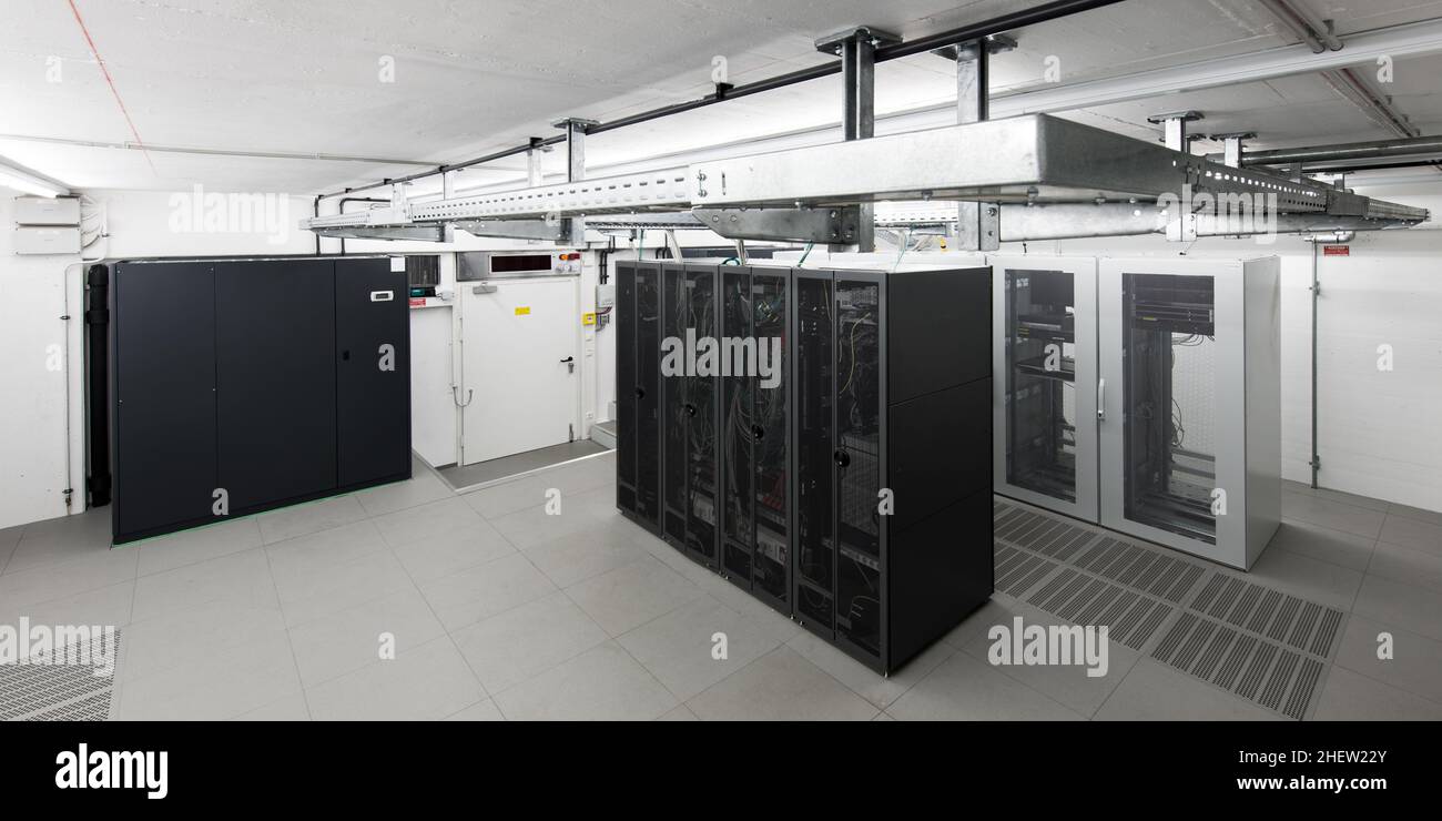 vista grandangolare di una piccola sala computer climatizzata con rack e vassoi per cavi Foto Stock