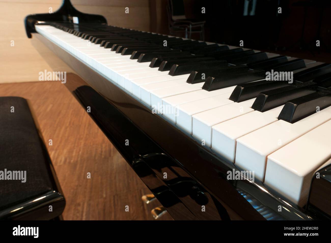 tasti bianchi della tastiera di un concerto di pianoforte nero con sgabello e pedali Foto Stock
