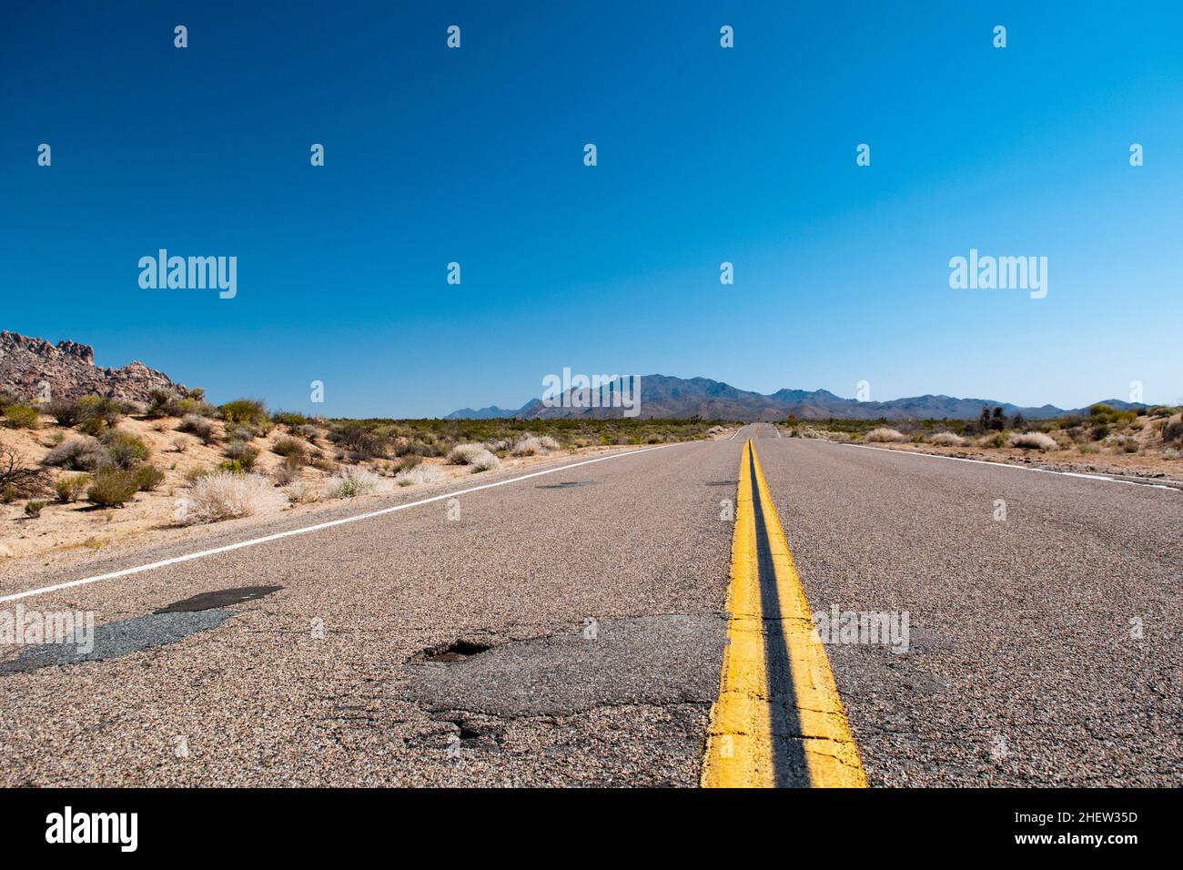 Una strada asfaltica obsoleta con strisce mediali arancioni in corso gettò un deserto negli Stati Uniti Foto Stock