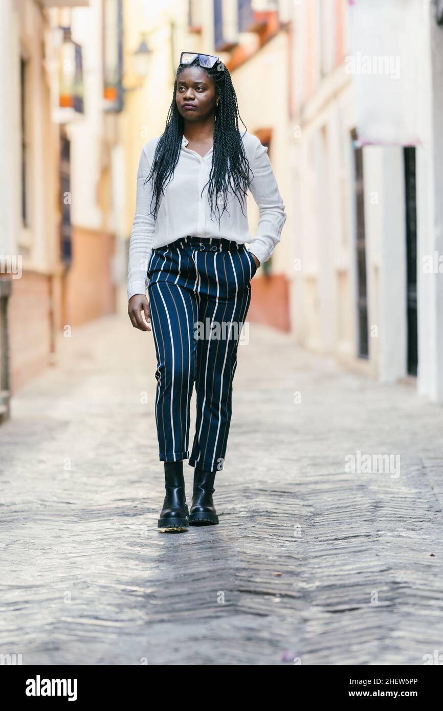 Donna africana con abiti moderni che camminano distratto all'aperto Foto Stock