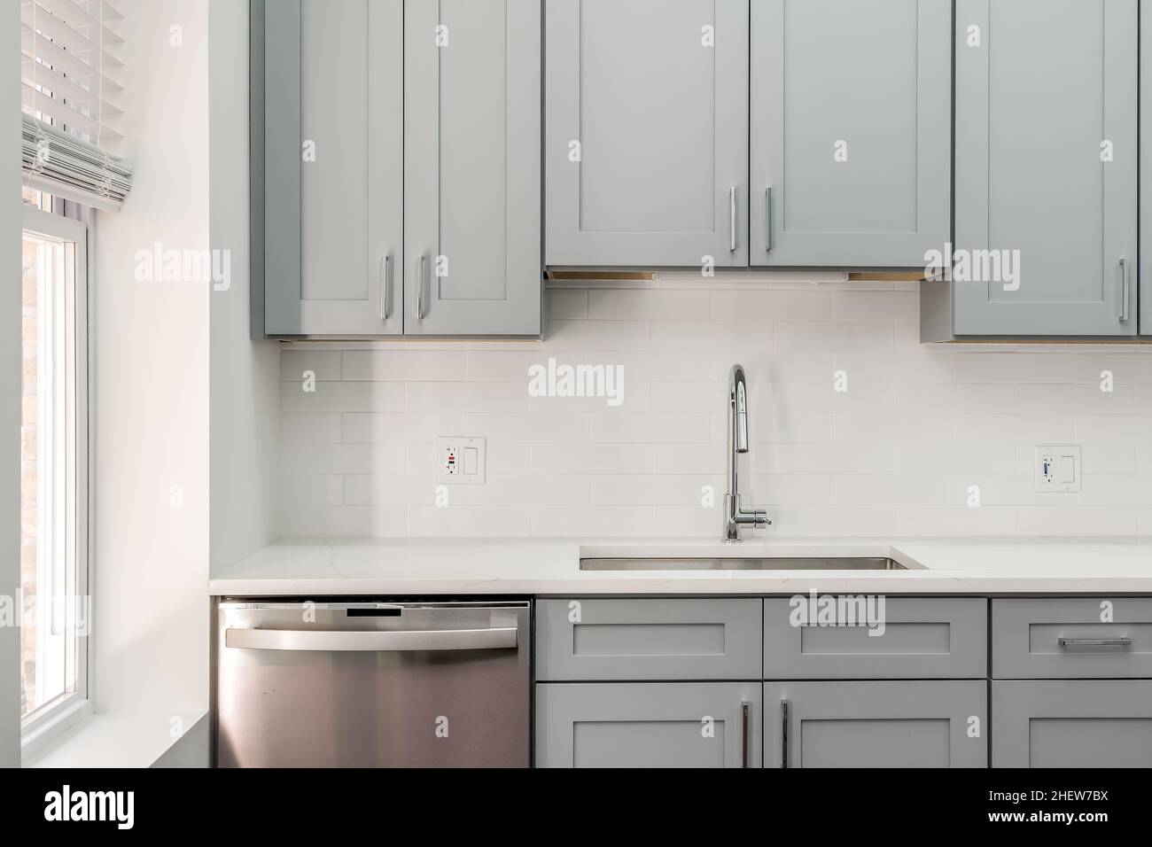 Cucina moderna in stile Condo grigio con armadi in stile Shaker grigio, backsplash Subway Tile e accessori in acciaio inossidabile Foto Stock