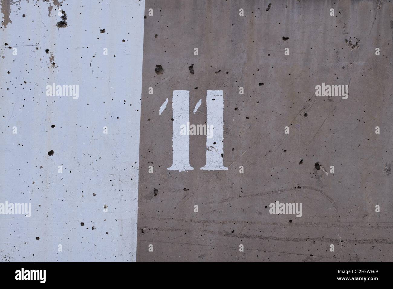 parete in cemento con due tonalità di grigio e il numero 11 dipinto su di essa Foto Stock