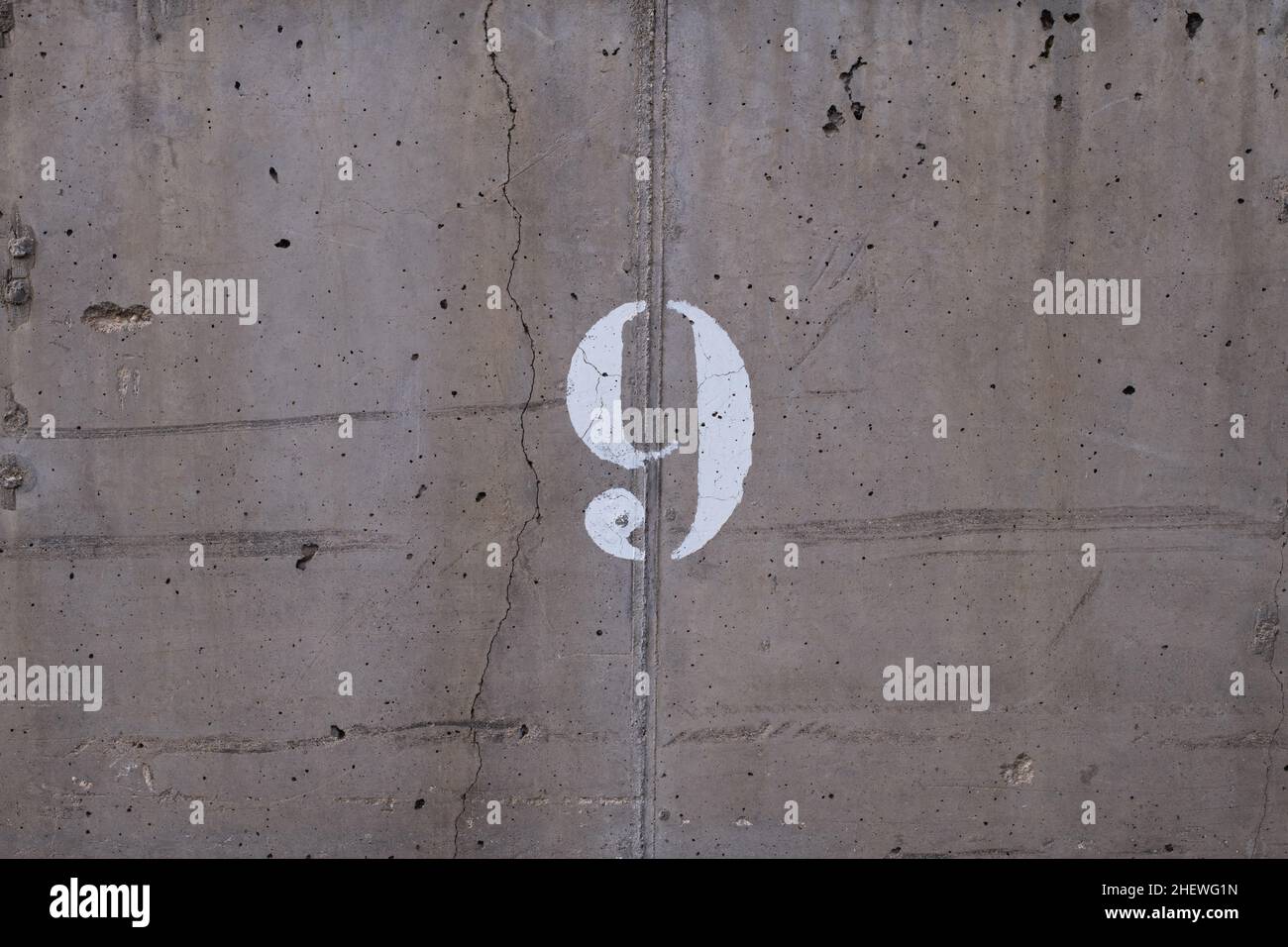 numero 9 digitato su un muro con una crepa attraverso di esso Foto Stock