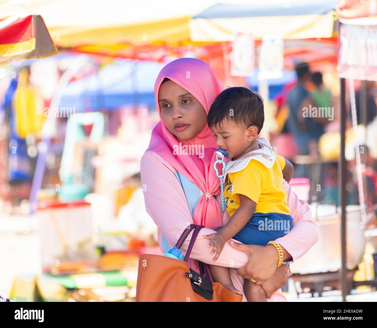 Donna musulmana che trasporta un bambino ad un mercato nello Stato di Kelantan, Malesia. Foto Stock