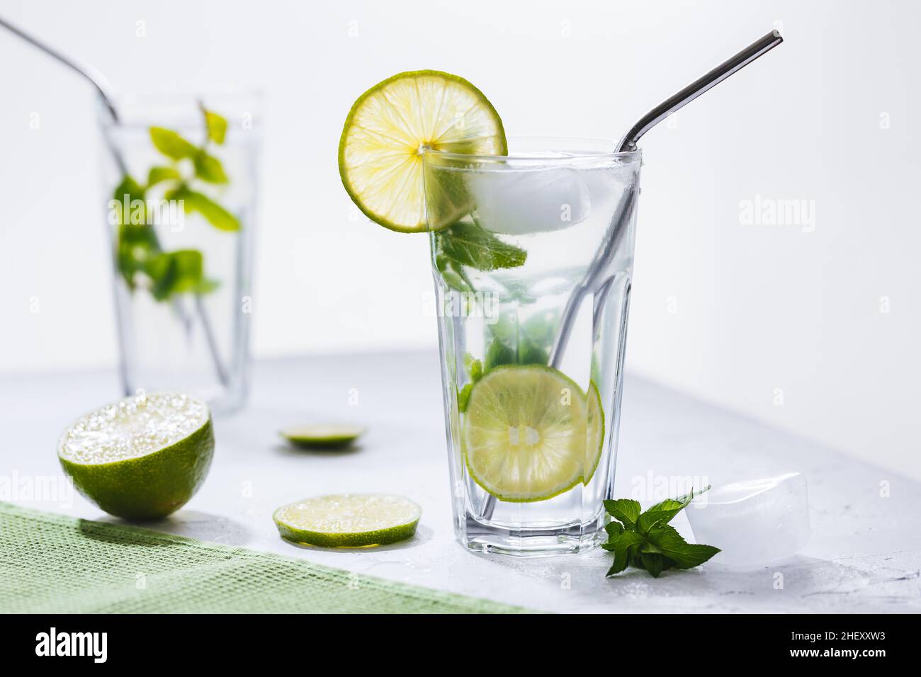Cocktail Mojito in vetro con calce, ghiaccio e menta serviti su uno sfondo luminoso Foto Stock