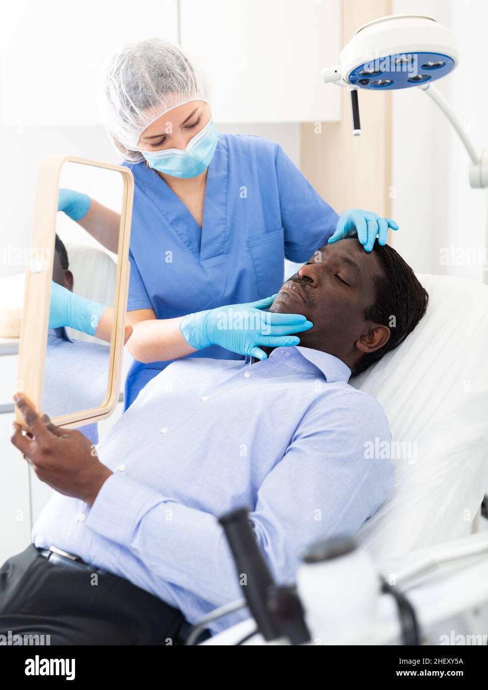 Donna estetista in maschera esame viso pelle di afro americano paziente  maschio Foto stock - Alamy