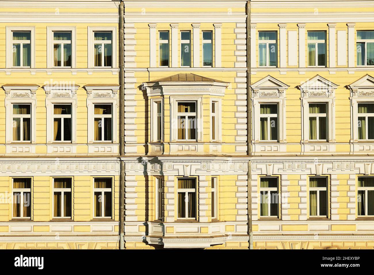 Edificio dall'architettura classica di colore giallo con finestre incorniciate sullo sfondo. Foto Stock