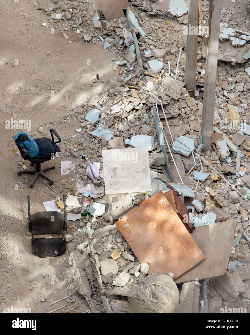 Luogo con cumulo di rifiuti scartati vicino a edificio abbandonato al giorno di sole. Relitti e rovine di edificio distrutto in città. Foto Stock