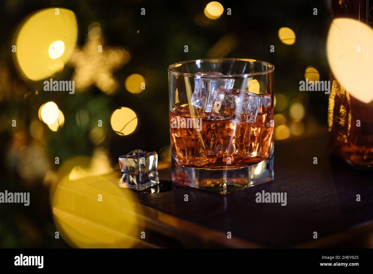 Bicchiere di whiskey o aperol spritz con cubetti di ghiaccio in un clima natalizio festivo con albero di Natale sullo sfondo Foto Stock