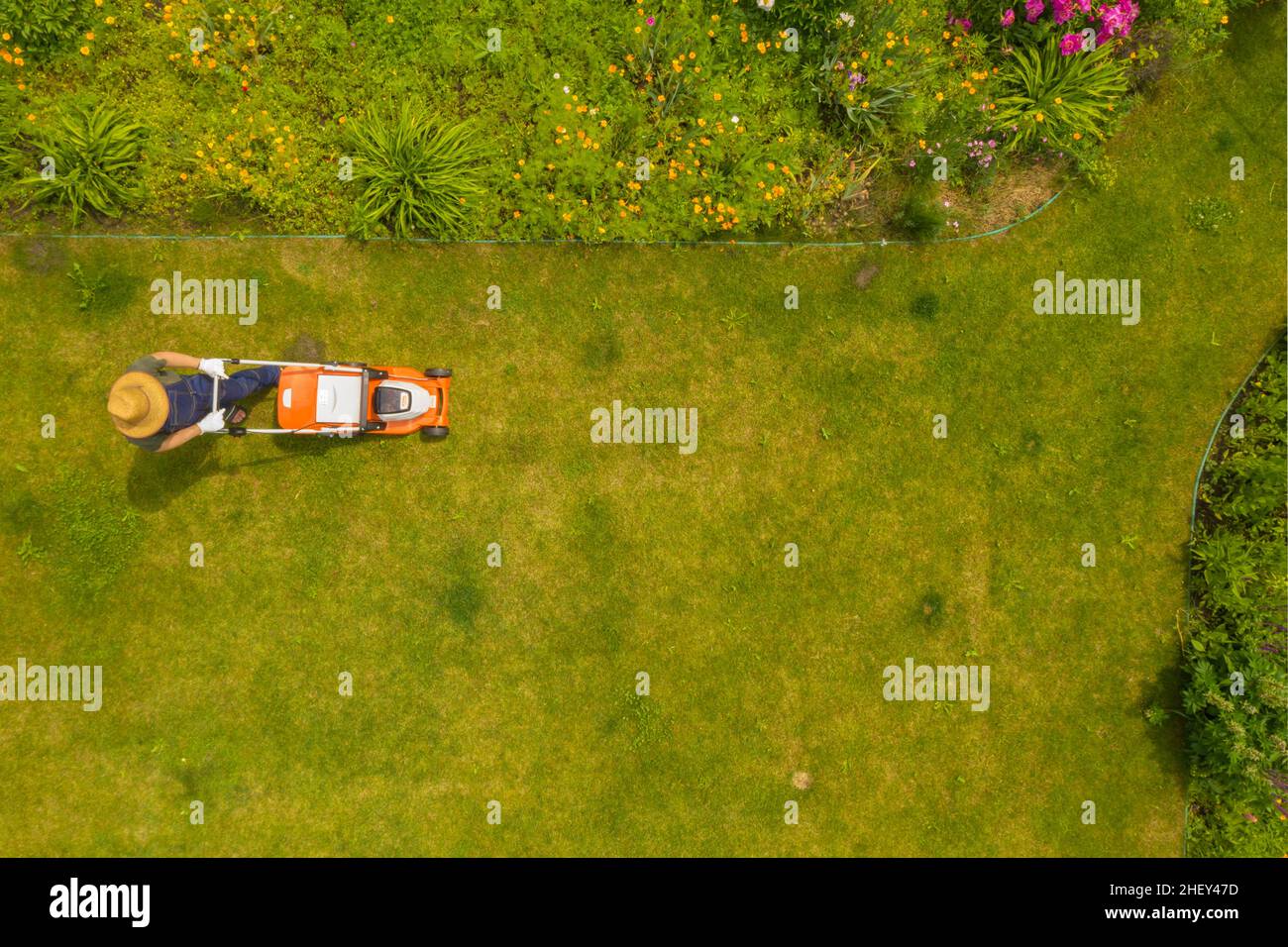 Un giovane uomo sta falciando un prato, vista dall'alto. Foto Stock
