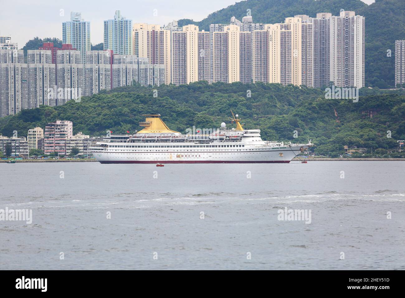 Nave da crociera 'Oriental Dragon' a Hong Kong, Cina del Sud, alti edifici residenziali, colline, nave galleggiante casinò, crociere, immagine navi passeggeri Foto Stock