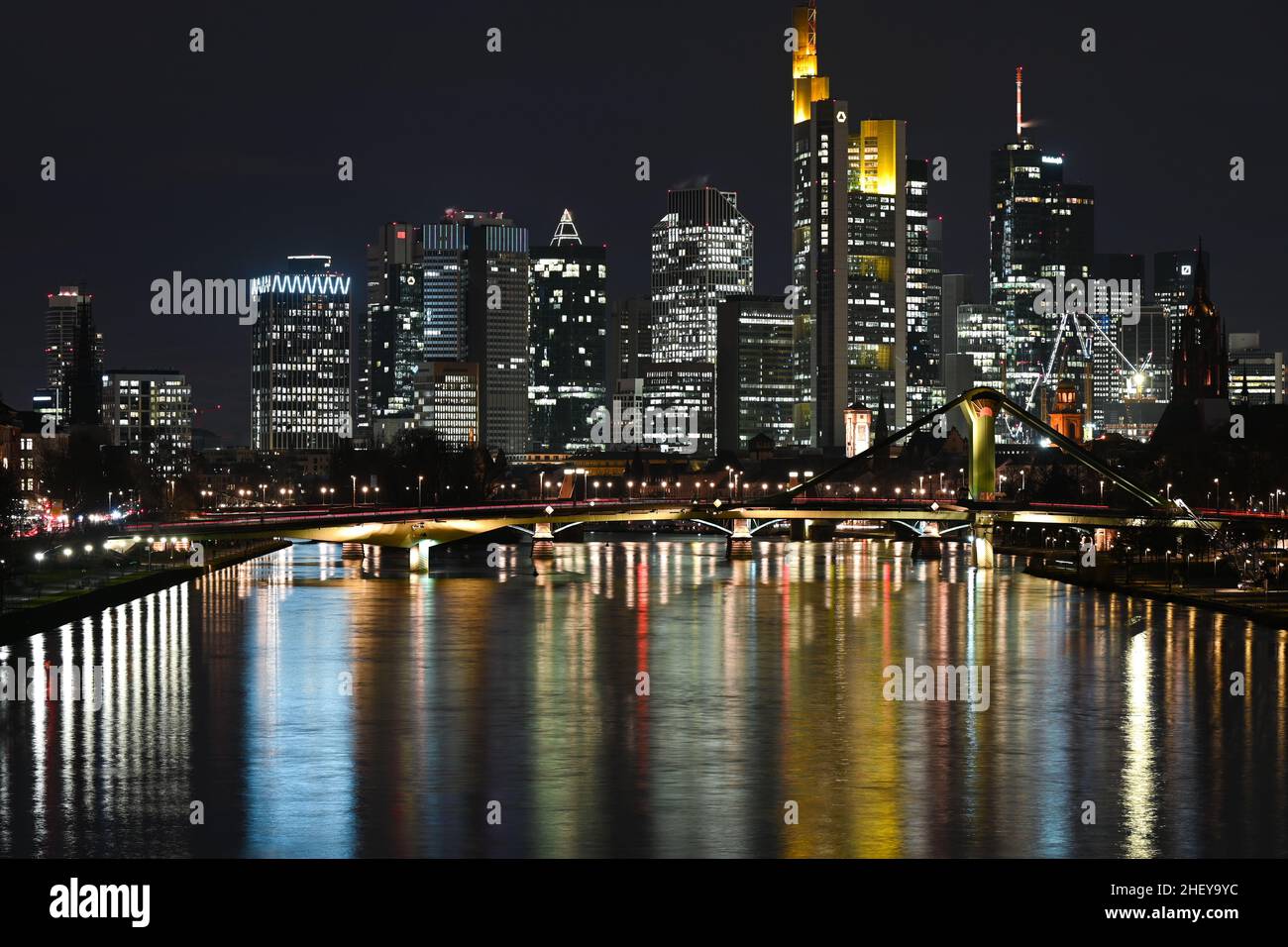 12 gennaio 2022, Hessen, Francoforte sul meno: Mentre gli uffici degli alti edifici di Francoforte sono illuminati in modo luminoso la sera, le luci colorate si riflettono nel fiume meno. Foto: Arne Dedert/dpa Foto Stock