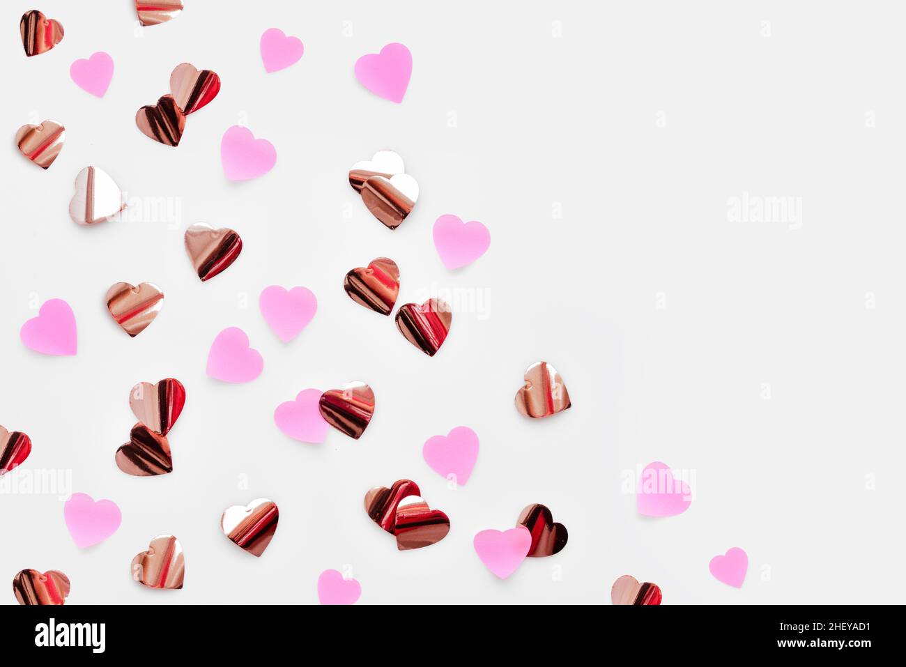 Vista dall'alto di piccoli cuori di carta su sfondo bianco. Confetti a forma di cuore. Elemento di disegno di bordo per striscione festivo, biglietto d'auguri, cartolina, matrimonio i Foto Stock