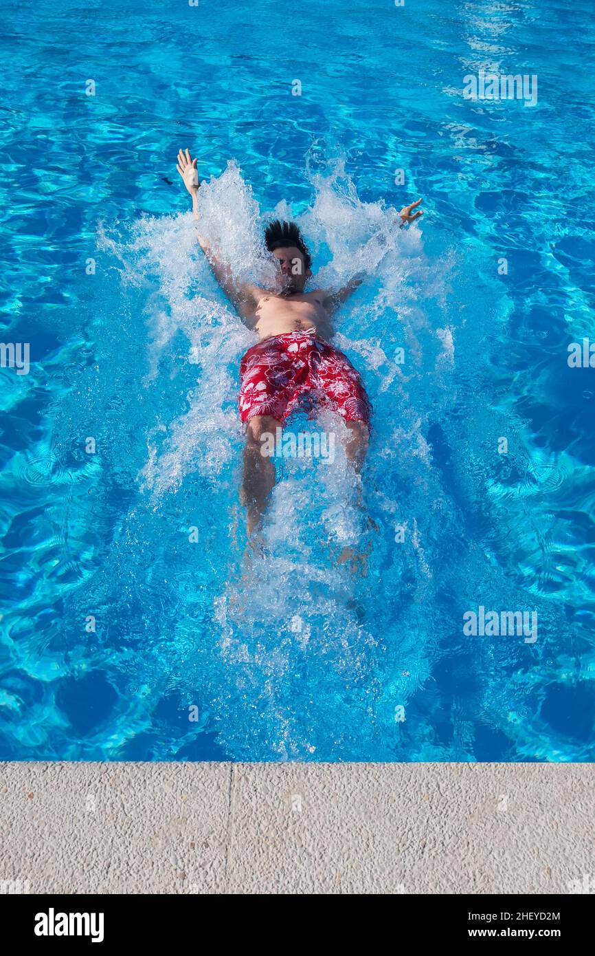 Il giovane uomo caucasico cade in acqua blu. Fine settimana estivo in piscina. Volare giù, stile di vita Foto Stock