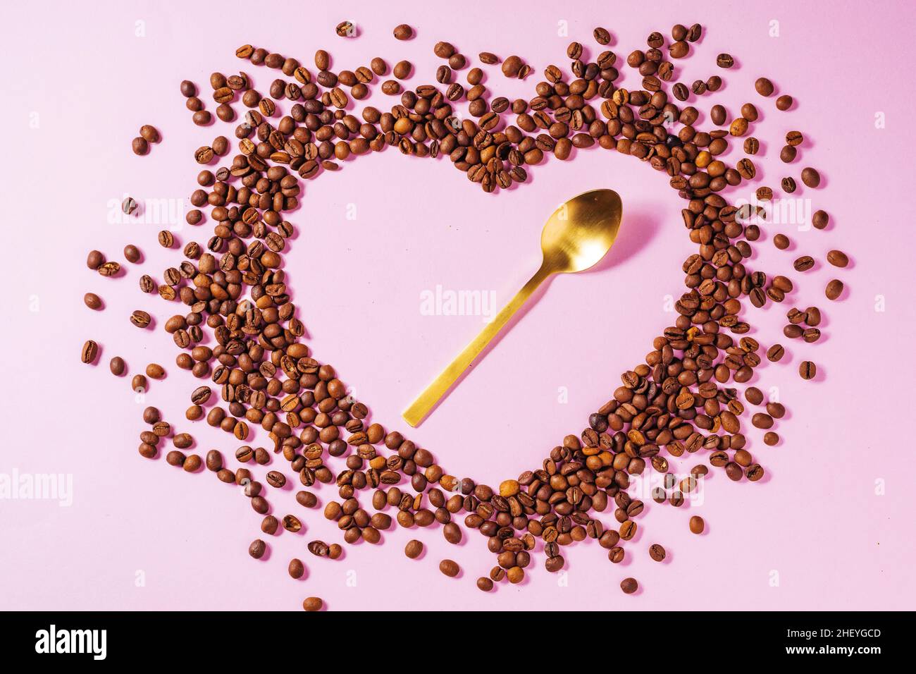 Tazza di caffè su sfondo viola con forma udibile realizzata con chicchi di caffè. Concetto ideale per una giornata di caffè più allegro, un giorno di baristi internazionali o Foto Stock