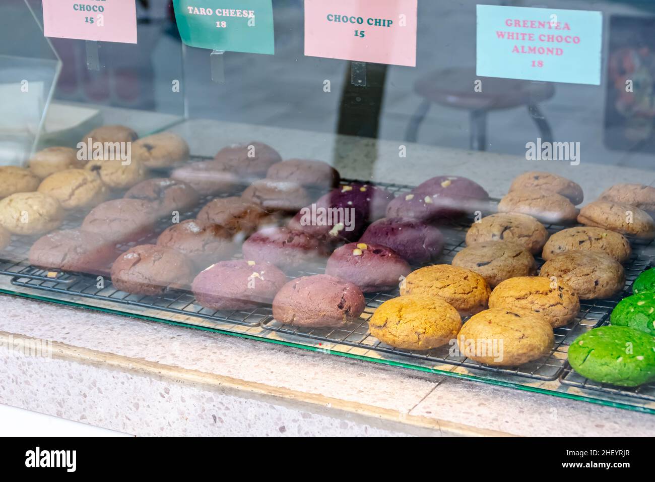 Deliziosi e gustosi biscotti colorati al forno visualizzati sul tappetino in acciaio nero all'interno della vetreria Foto Stock