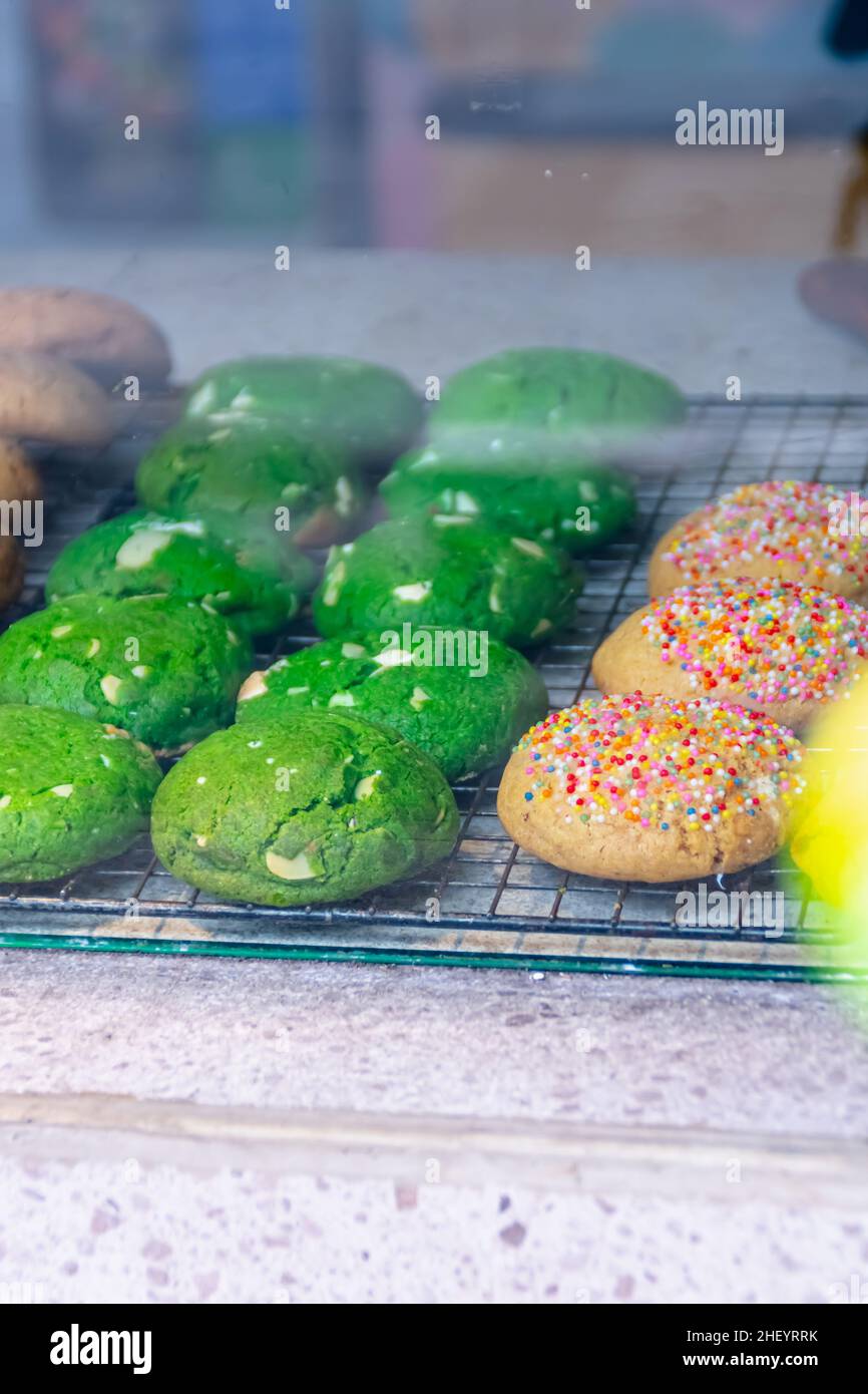 Deliziosi e gustosi biscotti colorati al forno visualizzati sul tappetino in acciaio nero all'interno della vetreria Foto Stock