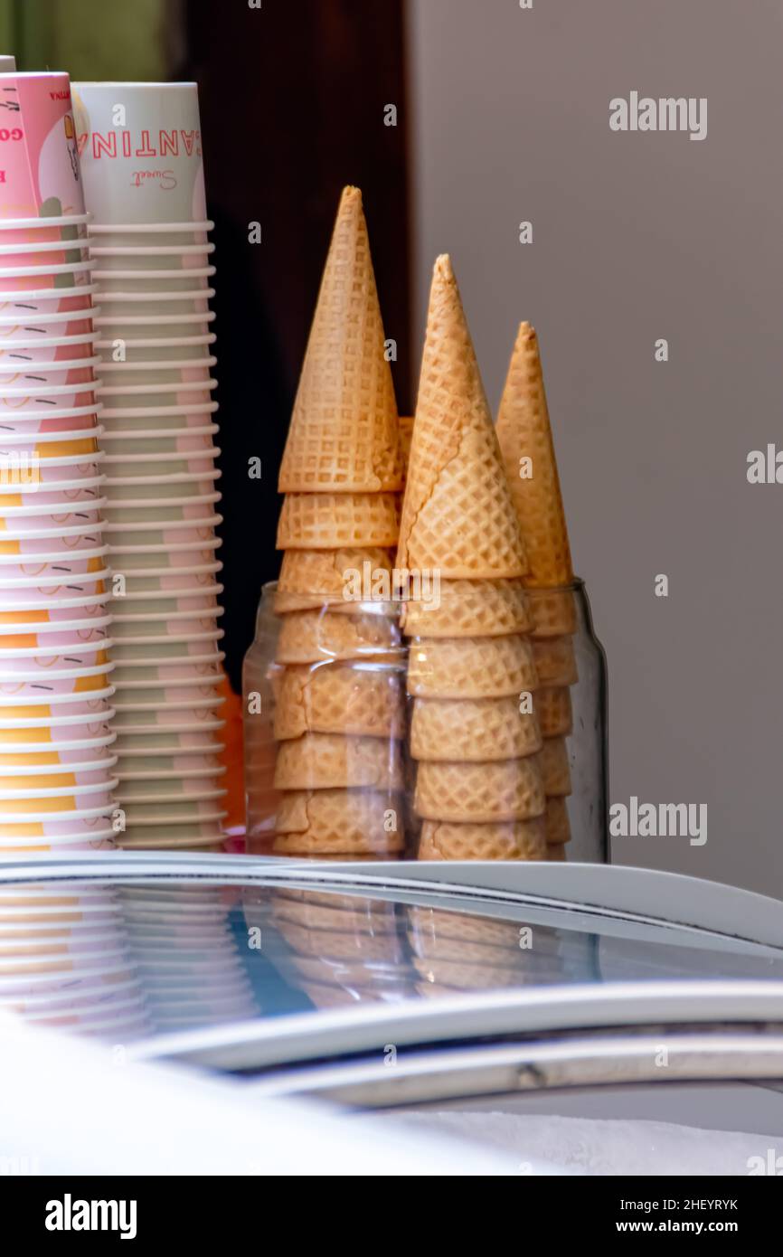 una pila di croccanti coni di cialde e tazze di gelato marroni si trova sul negozio Foto Stock