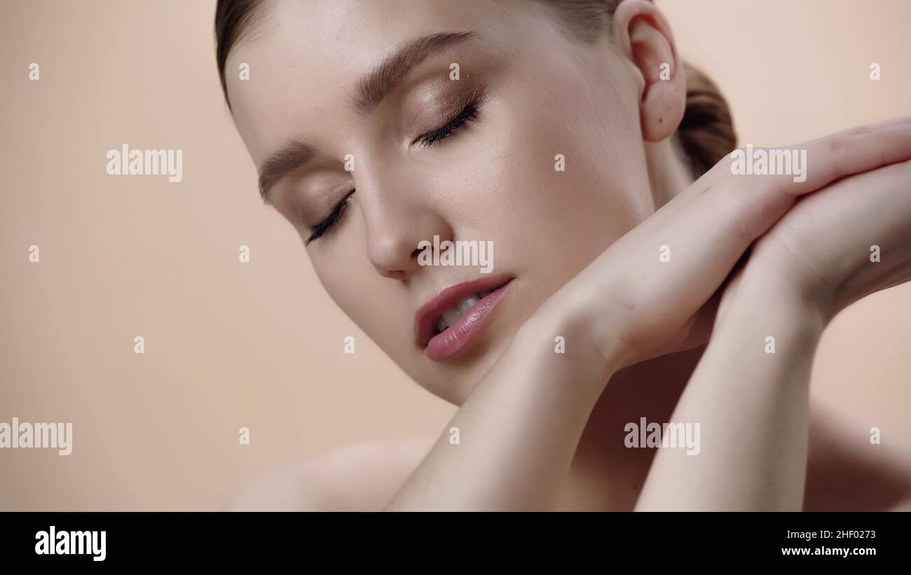 giovane donna con pelle perfetta e occhi chiusi isolati sul beige Foto Stock
