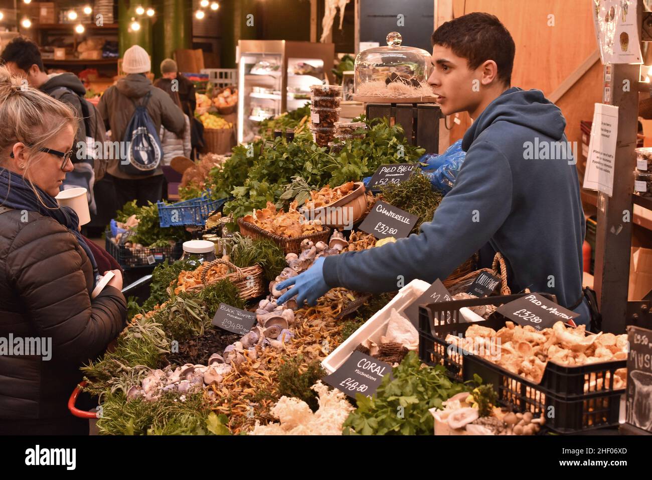 Negoziante presso il mercato Borough che vende varietà di funghi, Southwark London UK. Foto Stock