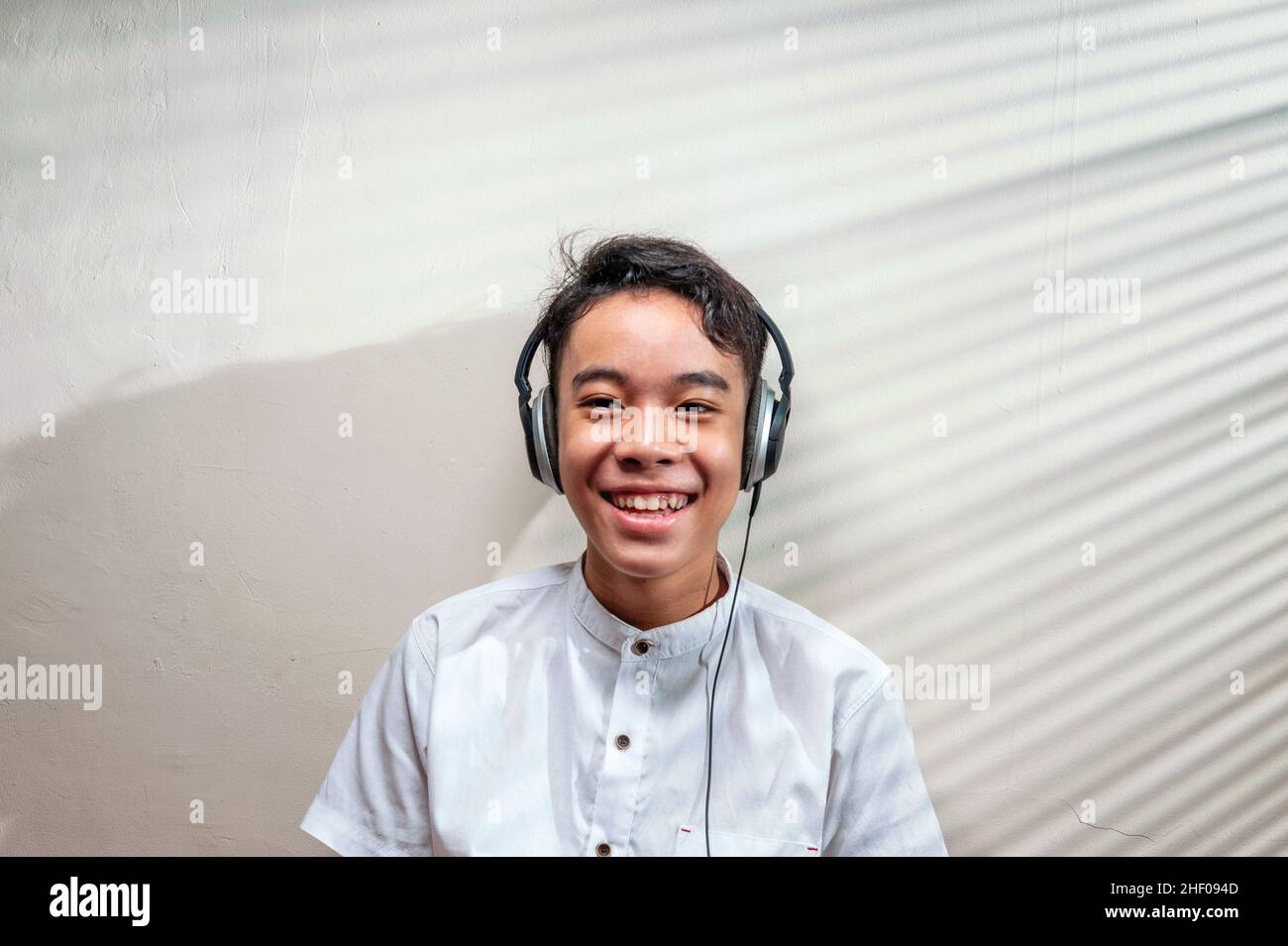 Ragazzo asiatico sorridente con cuffie in camera. Foto Stock