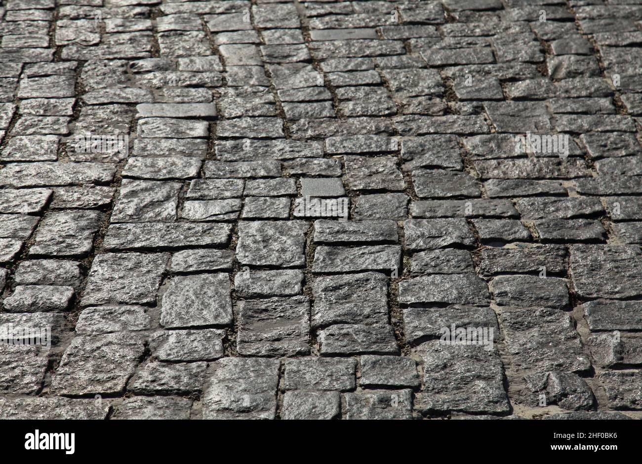 Vecchia strada pavimentazione pietra di granito ruvido pietra di forma irregolare primo piano. La struttura della strada in pietra, sfondo Foto Stock