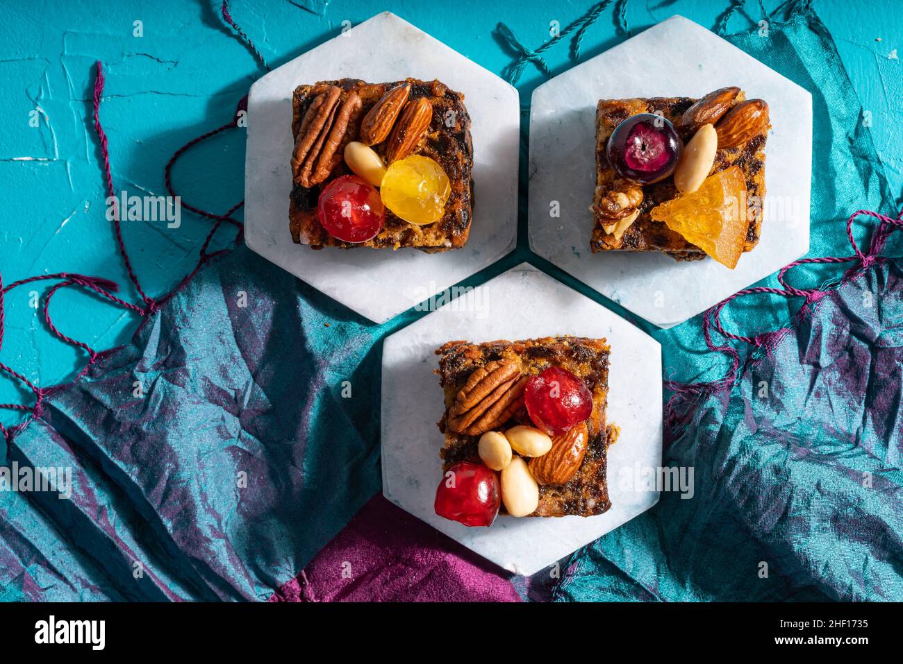 Ricco dolce budino natalizio carico di frutta secca, noci e spezie su un vibrante sfondo turchese orientale Foto Stock