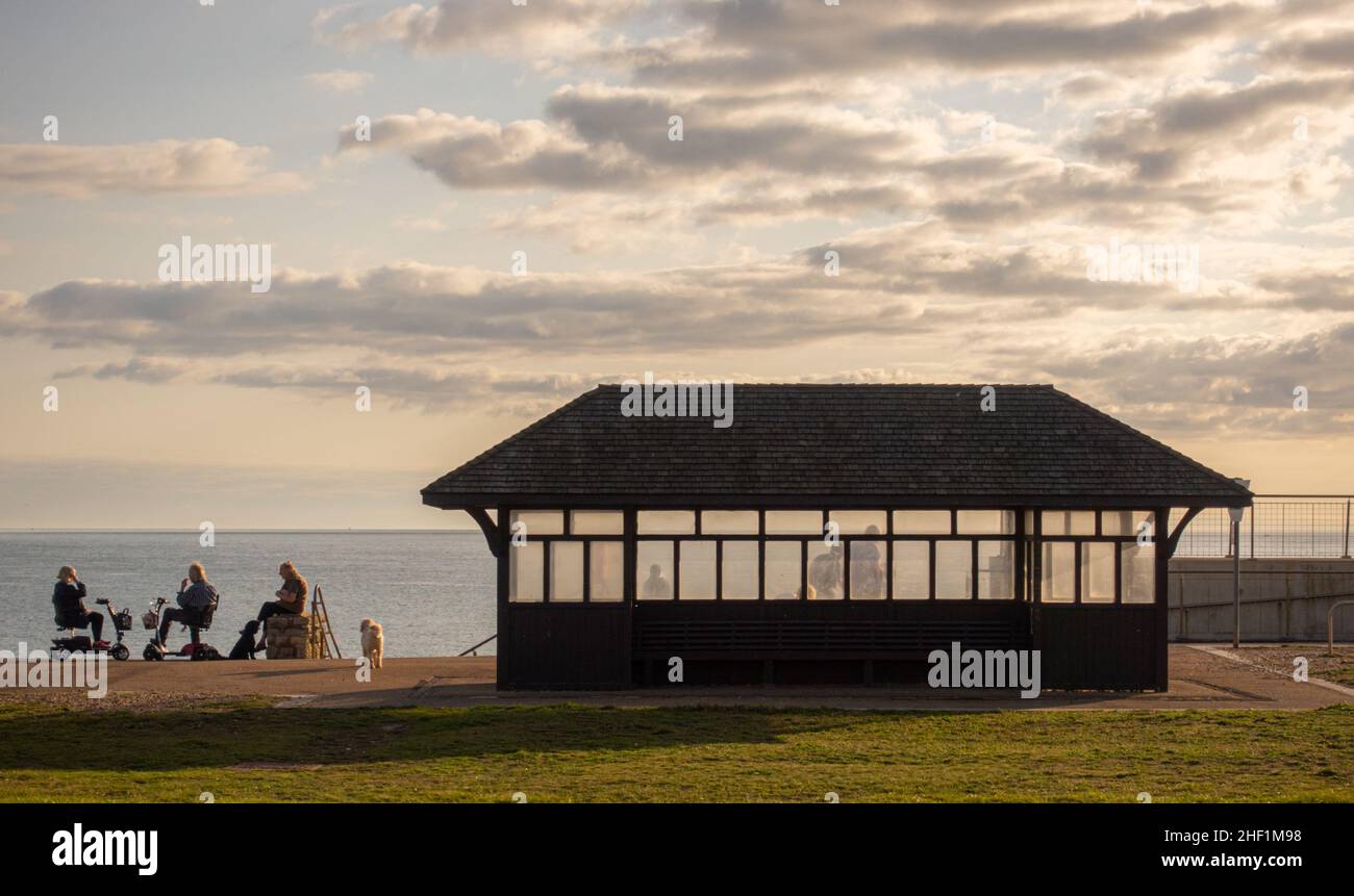 Rifugio sulla spiaggia a Milford sul Mare Hampshire, al tramonto con la gente che gode la luce della sera. Foto Stock