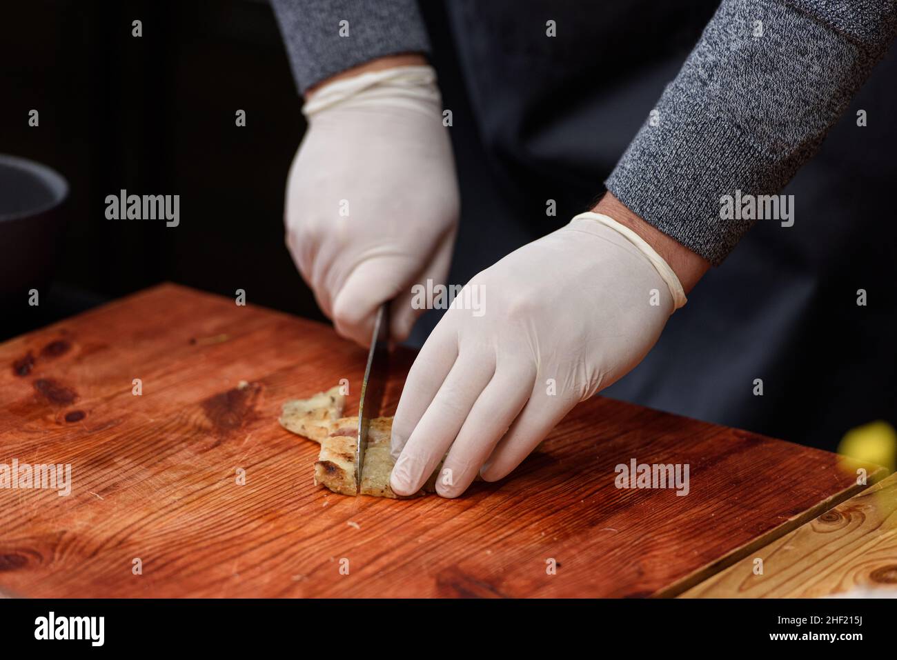 L'uomo taglia il pesce fritto, processo di cottura della zuppa Suquet de Peix con patate Foto Stock