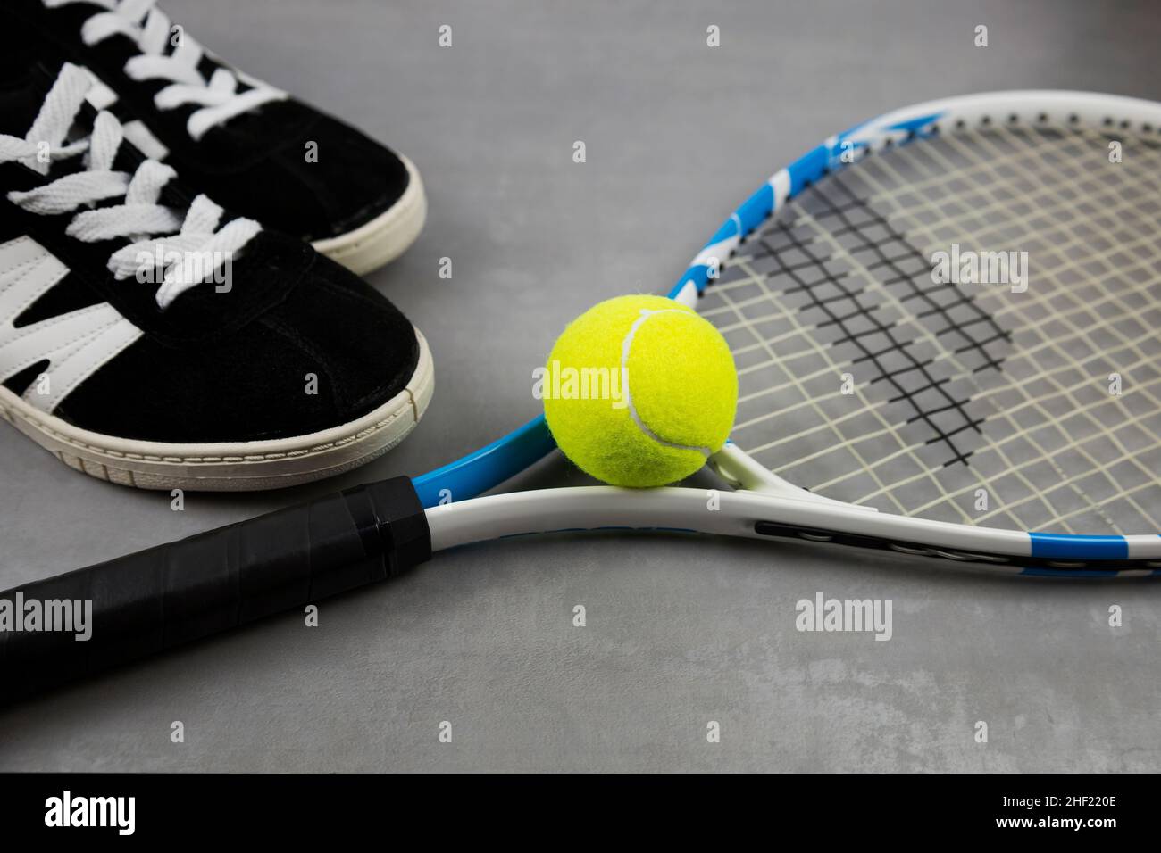 racket e palla da tennis su sfondo grigio. Giochi sportivi. Il campionato Foto Stock