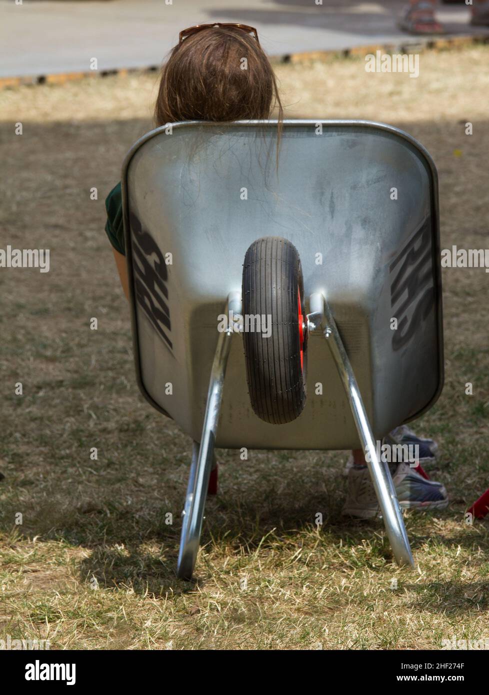 Un aiutante di pianta che prende un resto dagli acquisti pesanti di ferrying degli acquirenti. Seduti in una carriola. Spettacolo RHS a Hampton Court Foto Stock