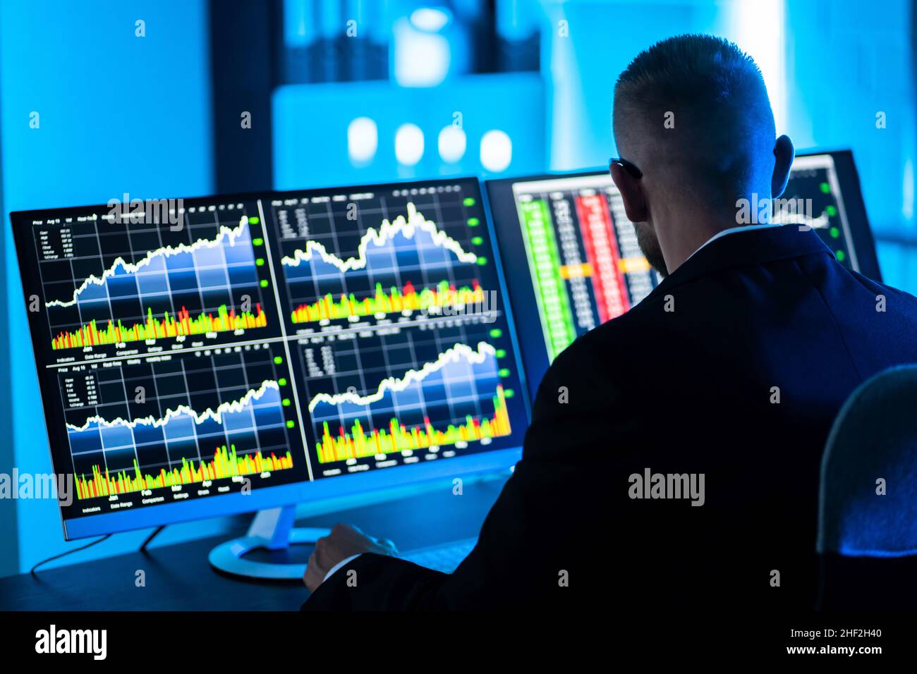 L'uomo commerciante di riserva usando i monitor multipli del calcolatore Foto Stock