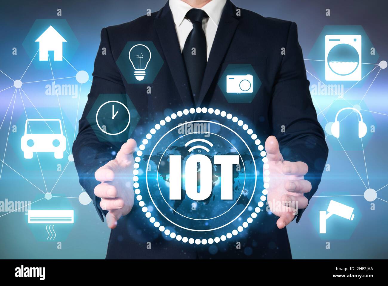 Un imprenditore tiene in mano il simbolo DELL'IOT, l'Internet delle cose. Connettività tramite Internet di elettrodomestici, orologi, auto e elettrodomestici intelligenti. Domoti Foto Stock