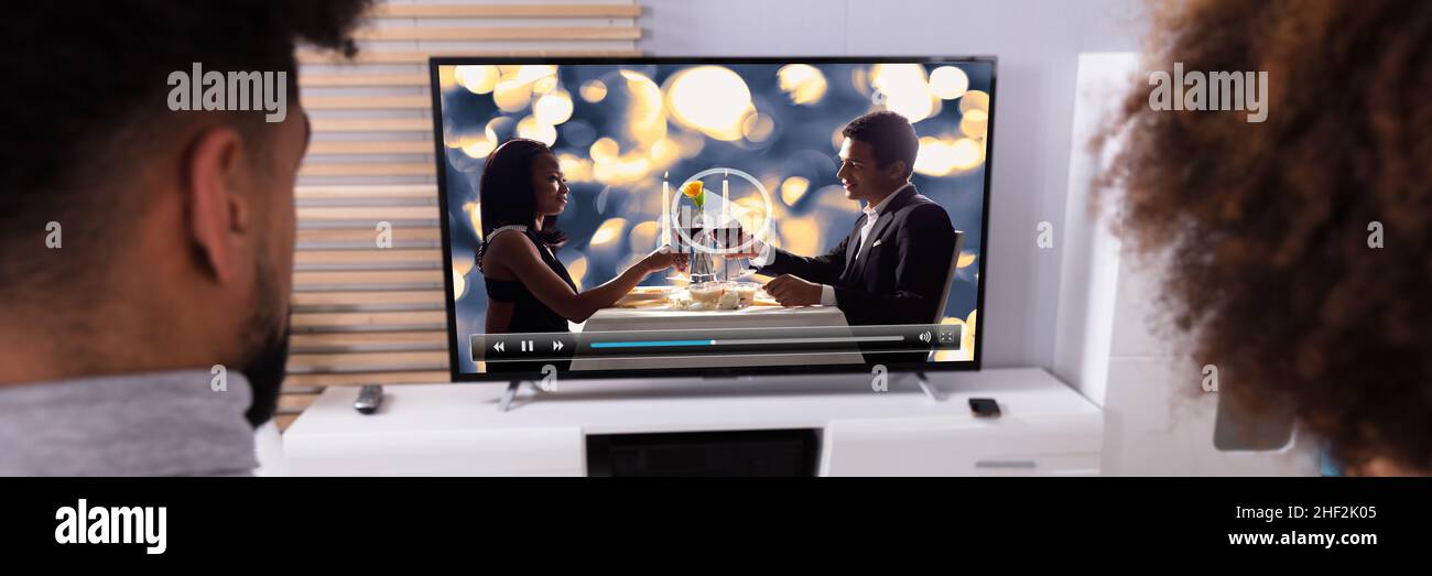Vista posteriore di una giovane guardando film in televisione a casa Foto Stock