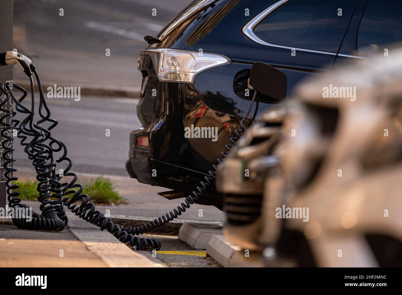 Auto elettrica alla stazione di ricarica con il cavo di alimentazione collegato. Concetto di energia alternativa ecocompatibile. Tecnologia. Foto Stock