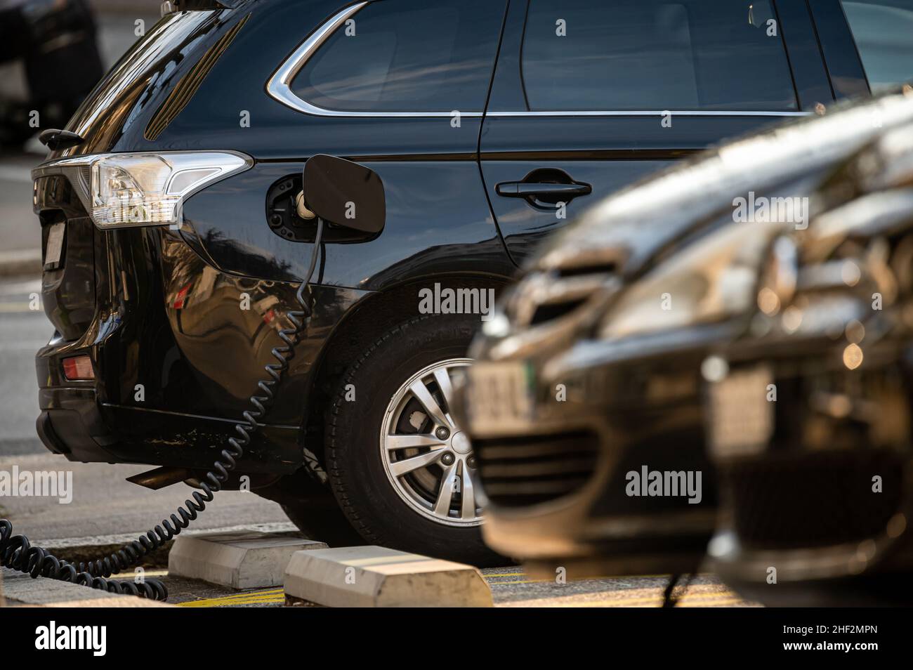 Auto elettrica alla stazione di ricarica con il cavo di alimentazione collegato. Concetto di energia alternativa ecocompatibile. Tecnologia. Foto Stock