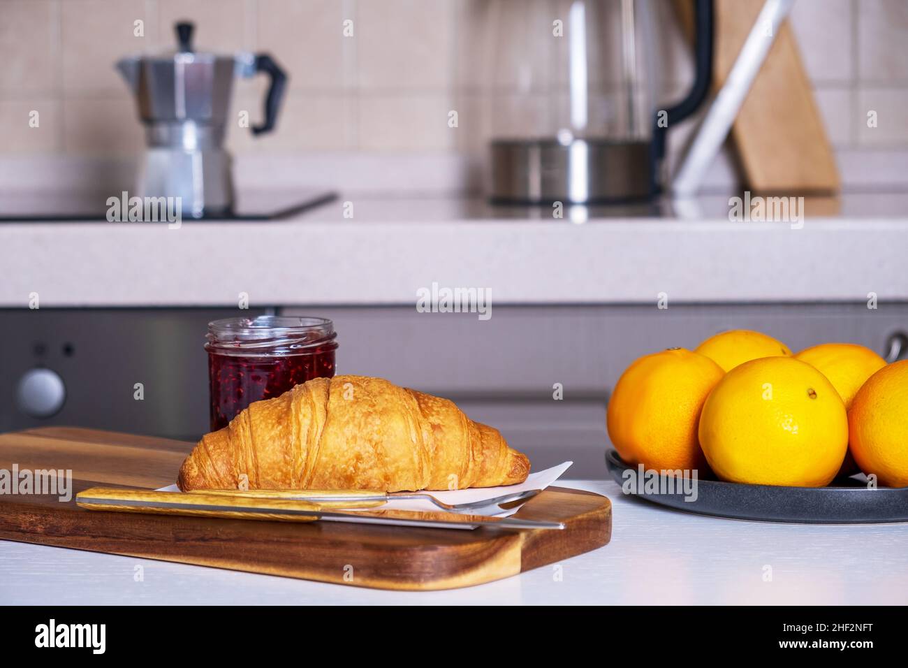 Croissant fresco e marmellata e piatto di arance si trovano sul tavolo da cucina Foto Stock